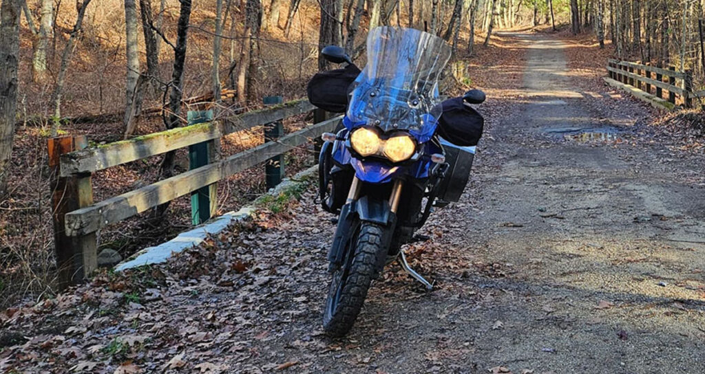 Motorcycle on the side of the road during the fall with dappled sunlight